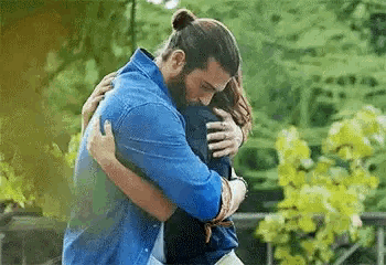 a man and woman hugging each other in a park .