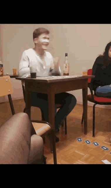 a man with a mask on his face sits at a table playing a game