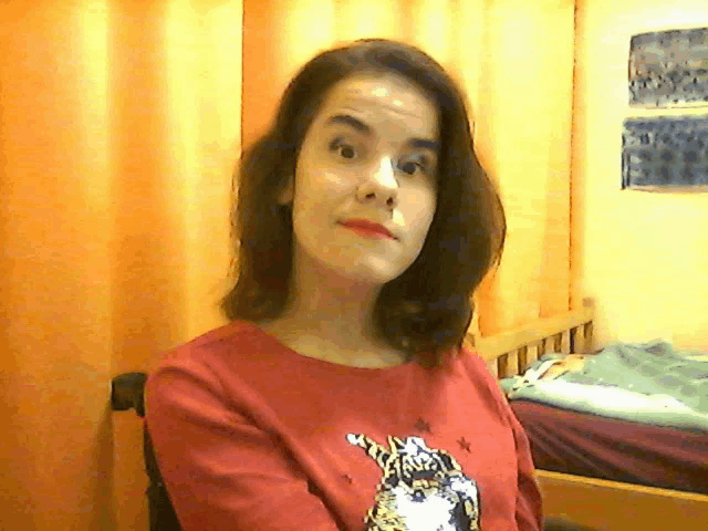 a woman wearing a red shirt with a cat on it looks at the camera