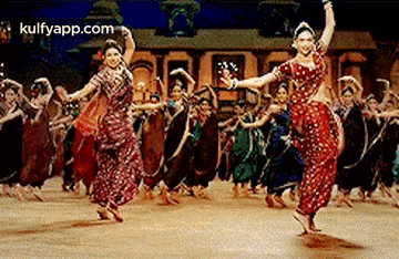 a group of women are dancing in front of a crowd of people .