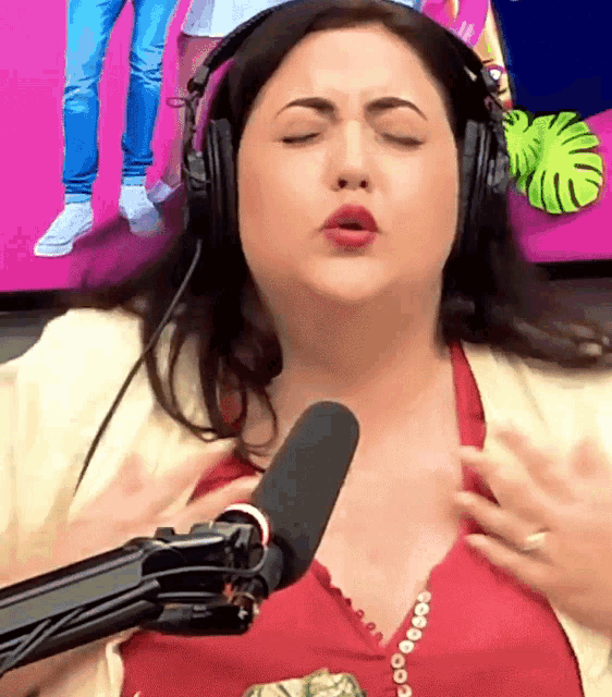a woman wearing headphones and a red shirt is singing into a microphone