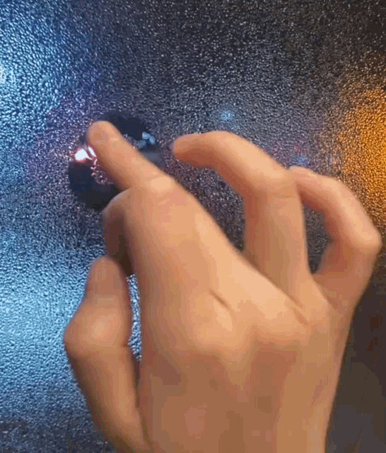 a person 's hand is pressing a button on a glass door