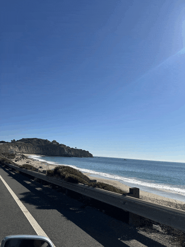 a car is driving down a highway with a view of a beach