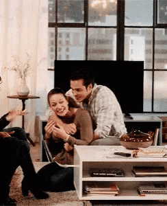 a man is hugging a woman while sitting on the floor in a living room