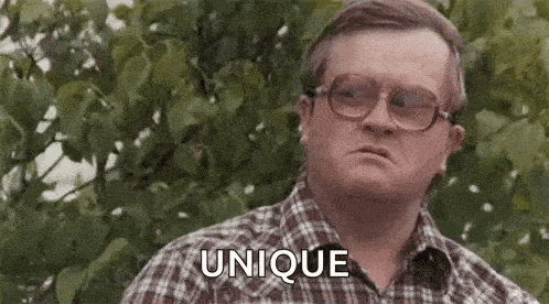 a man in a plaid shirt and glasses is standing in front of a tree .