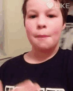a young boy in a black shirt is making a face and has a heart on his forehead that says like