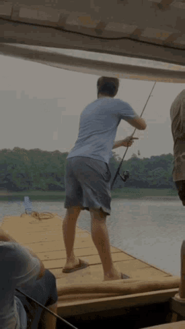 a man standing on a dock holding a fishing pole