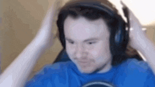 a man wearing headphones and a blue shirt is sitting in front of a computer screen .