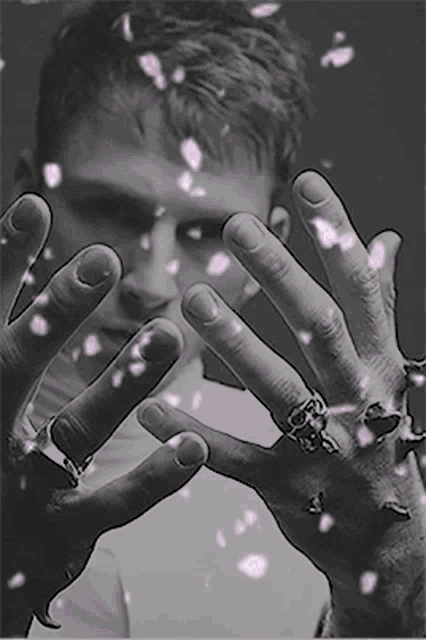 a black and white photo of a man 's hands with flowers falling on them