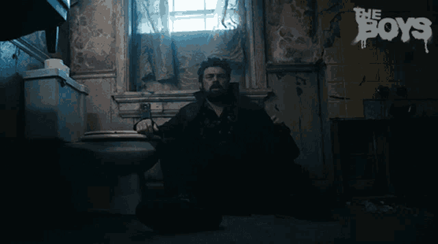 a man is sitting on a toilet in a bathroom with the boys written on the wall behind him