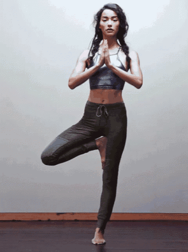 a woman in a crop top and leggings is practicing yoga