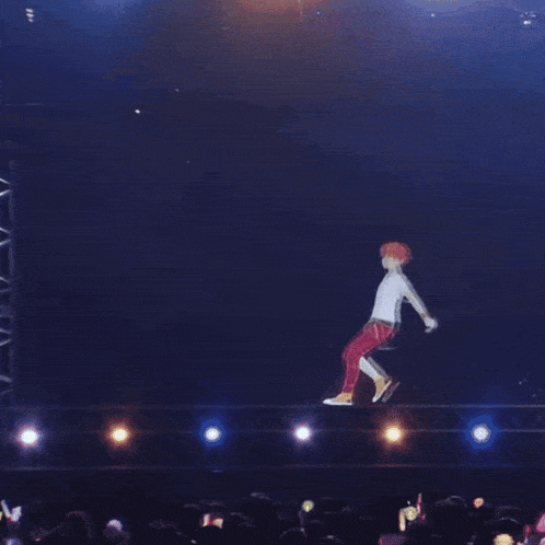 a man in red pants is dancing on a stage