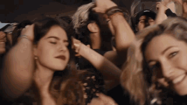 a group of people are dancing in a crowd and one woman has red lipstick