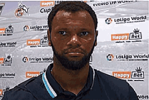a man with a beard is standing in front of a wall with laliga world written on it