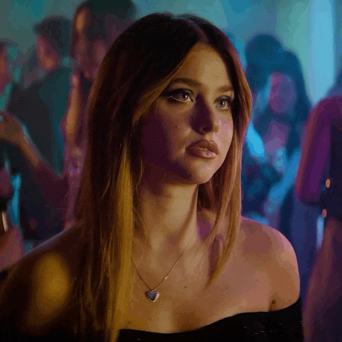 a woman wearing a black off the shoulder top and a heart shaped necklace