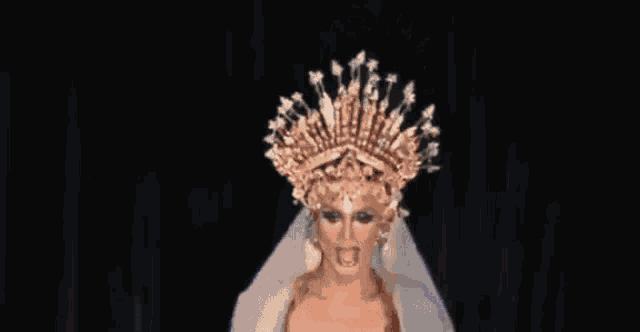 a drag queen is wearing a crown and a white veil .