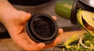 a person is holding a black object in their hands in front of a vegetable chopper .