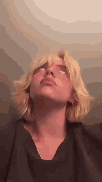 a close up of a person with blonde hair looking up at the sky .