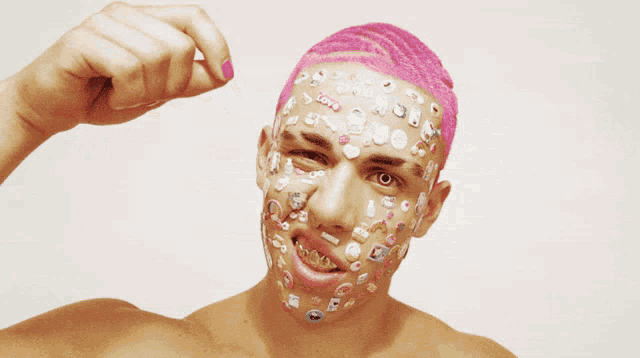a man with pink hair has many stickers on his face including one that says " love "