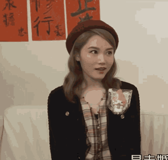 a woman wearing a red hat and a plaid shirt is sitting on a couch