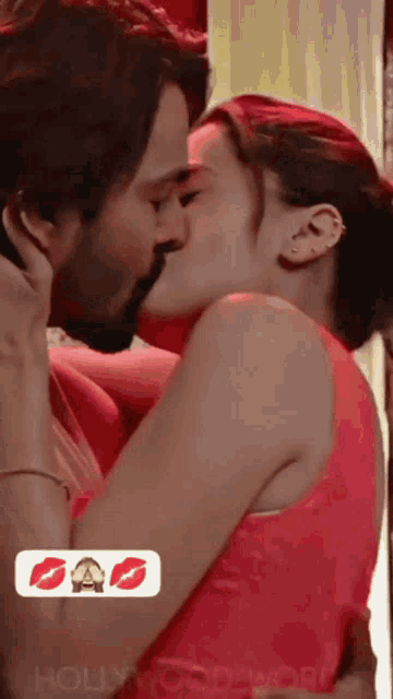 a man and a woman are kissing in front of a sign that says ' hollywood ' on it .