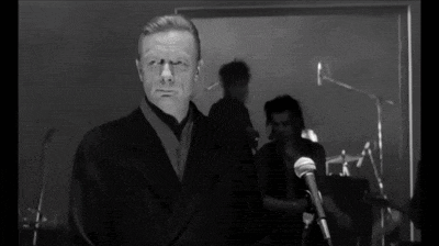 a man in a suit is standing in front of a microphone in a black and white photo