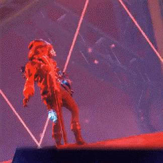 a man in a blue suit is standing on a stage in front of a fire