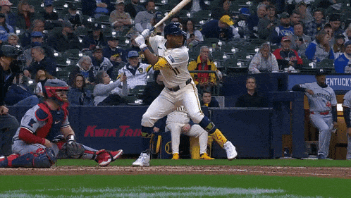 a baseball player swings his bat at a pitch in front of a kwik trolley advertisement