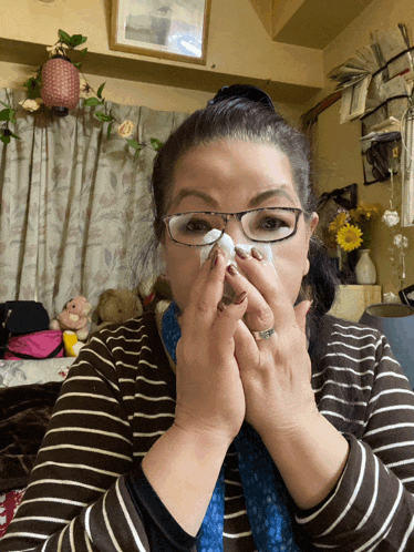 a woman wearing glasses is blowing her nose