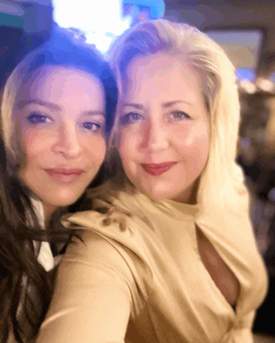 two women are posing for a picture and one is wearing a hood