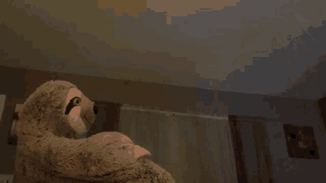 a stuffed sloth is being held by a man in a living room