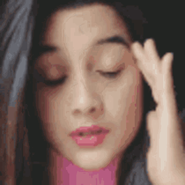a woman is holding her hand to her forehead .