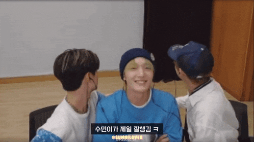 a man in a blue hat is being kissed by two other men with a caption that says @sminlover