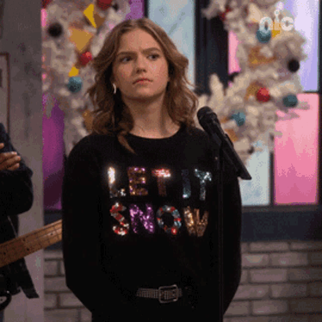 a girl is wearing a black sweater that says let it snow