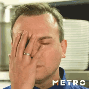 a man with a ring on his finger is covering his face