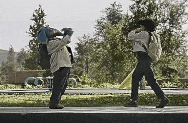 a man with a backpack is walking next to another man with a mask on their head