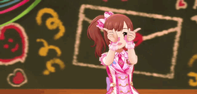 a girl in a pink dress making a peace sign in front of a blackboard