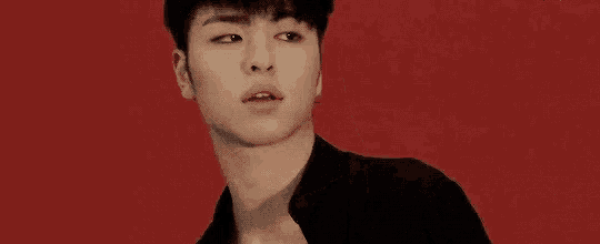a close up of a young man 's face with a red background