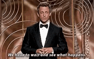 a man in a tuxedo and bow tie is giving a speech and says `` we have to wait and see what happens ''