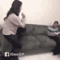 a woman is dancing in front of a man on a couch .