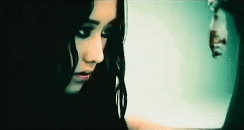 a close up of a woman 's face with a reflection of a man in the mirror .