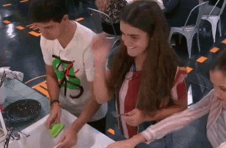a man and a woman are washing dishes in a sink .