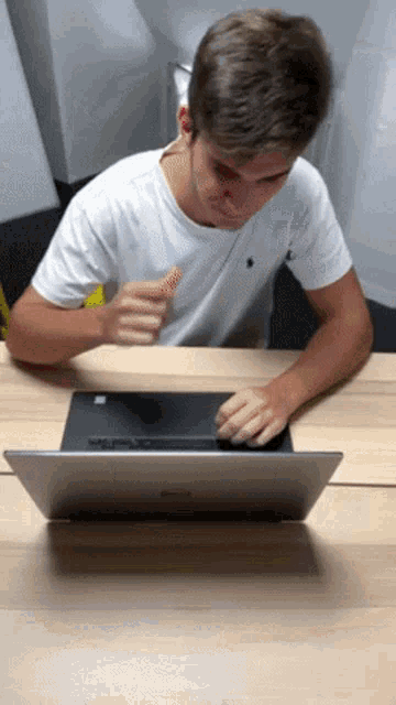 a young man sitting at a desk using a laptop computer