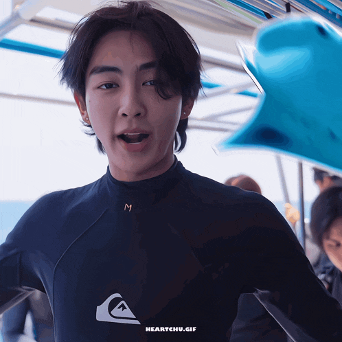 a young man wearing a wetsuit with the letter m on the chest