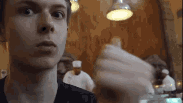 a young man is sitting at a table in a restaurant looking at the camera .