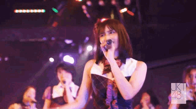 a woman singing into a microphone with the number 48 on the bottom right