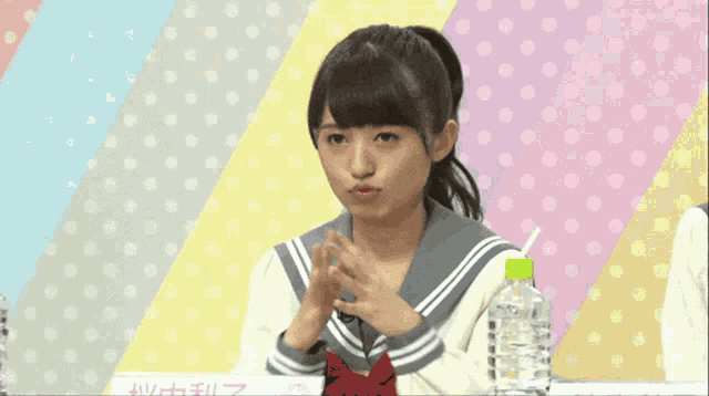 a girl with a ponytail is making a funny face in front of a polka dot background