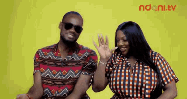 a man and a woman are sitting next to each other on a yellow background and smiling .