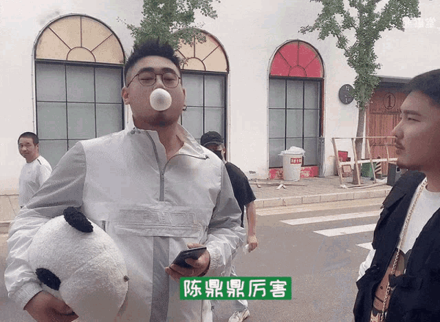a man blowing a bubble gum while holding a stuffed panda