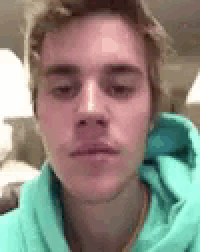 a close up of a young man 's face wearing a blue hoodie .